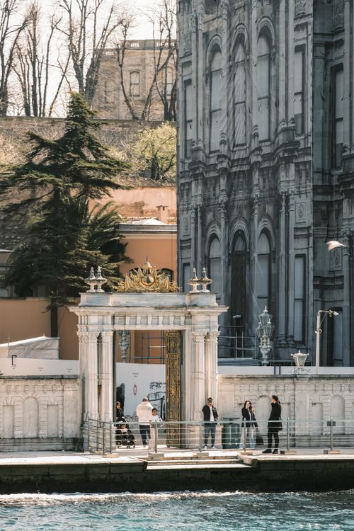 Free Elegant white gate at waterfront with historic building and people in background. Stock Photo