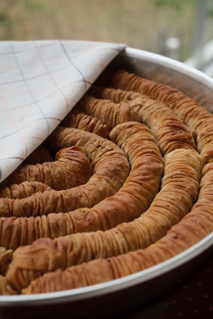 Delicious spiral pastry with crispy layers, freshly baked in a tray, covered with a cloth.