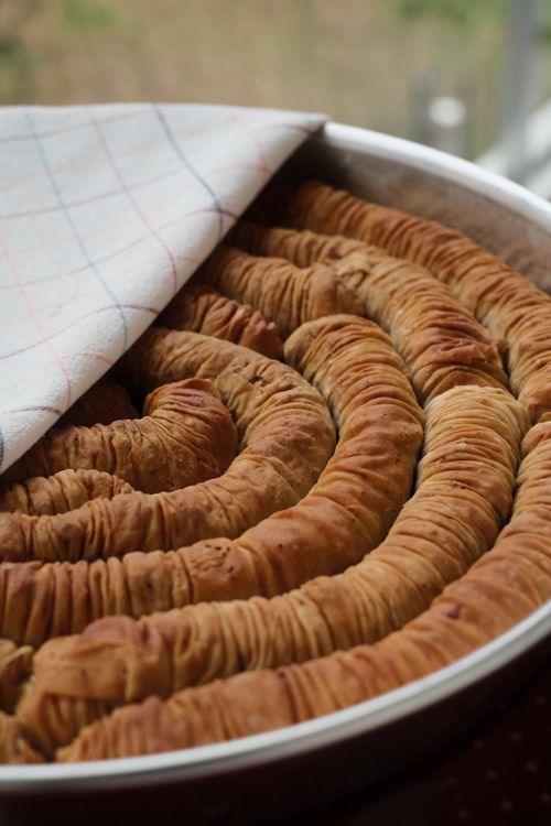 Free Delicious spiral pastry with crispy layers, freshly baked in a tray, covered with a cloth. Stock Photo