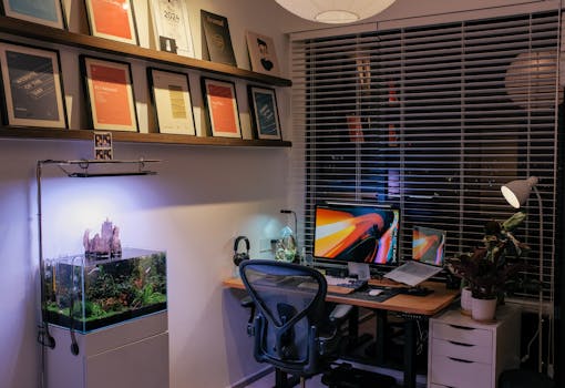 A stylish home office setup featuring dual monitors, modern fixtures, and an aquarium.
