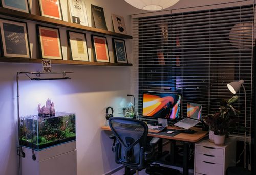 Free A stylish home office setup featuring dual monitors, modern fixtures, and an aquarium. Stock Photo