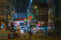 夜晚，香港繁忙的城市街道上霓虹闪烁，行人往来