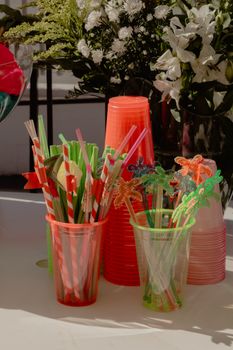 Brightly colored plastic cups and straws arranged for a tropical-themed celebration.