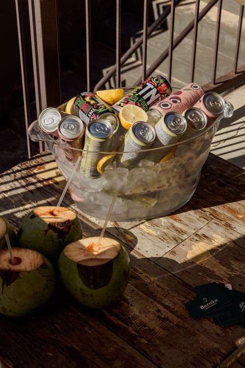 Free A vibrant setup of canned drinks and fresh coconuts on a rustic table in São Paulo. Stock Photo