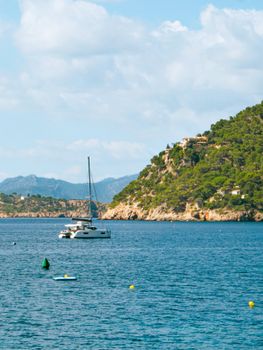 Picturesque coastal scene with a boat and lush hills in Mallorca, Spain.