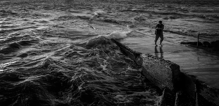 Monochrome Photo Of Person Fishing On Seashore