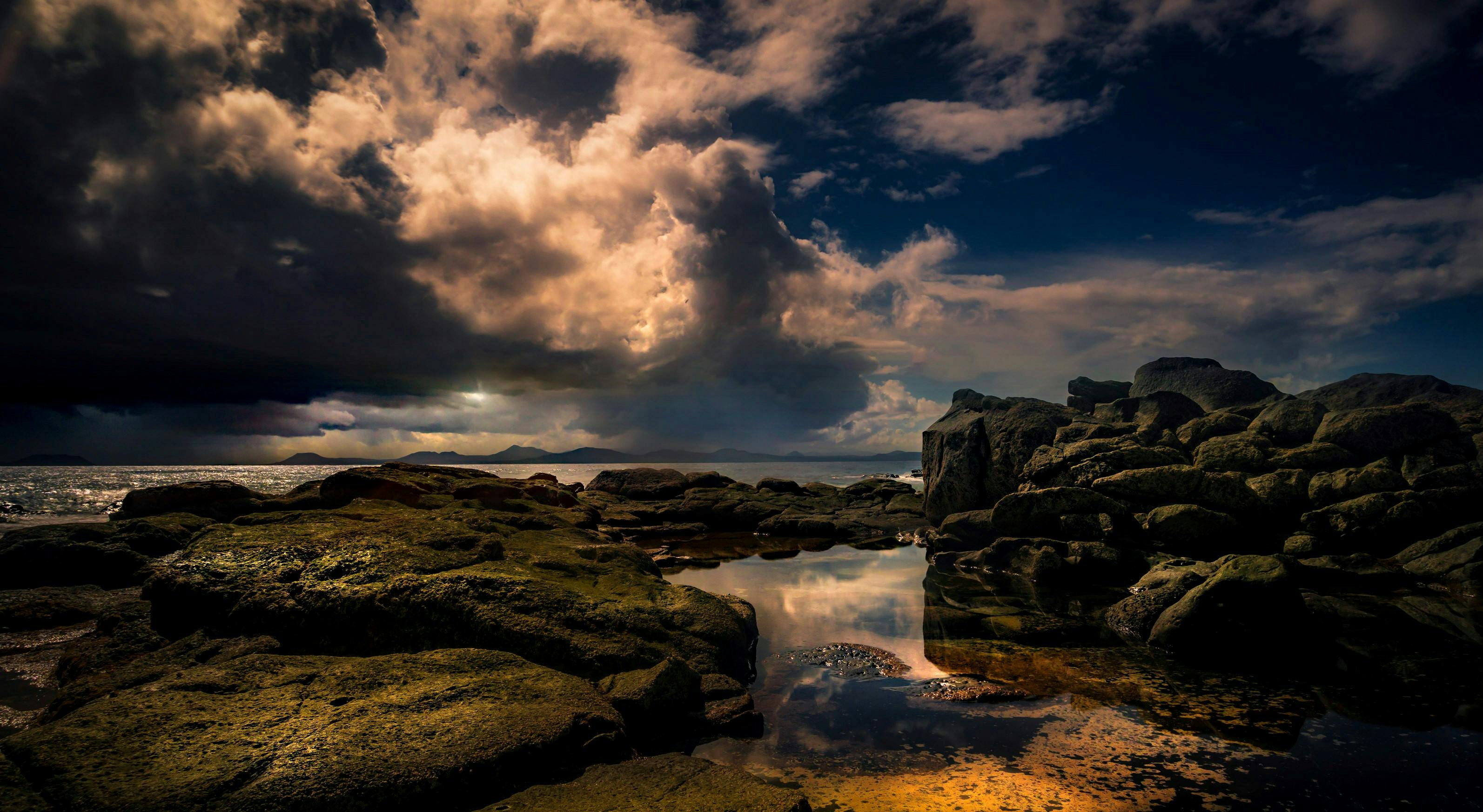 黄金时分，壮观的云层下，雄伟的岩石海岸线衬托出宁静的海景