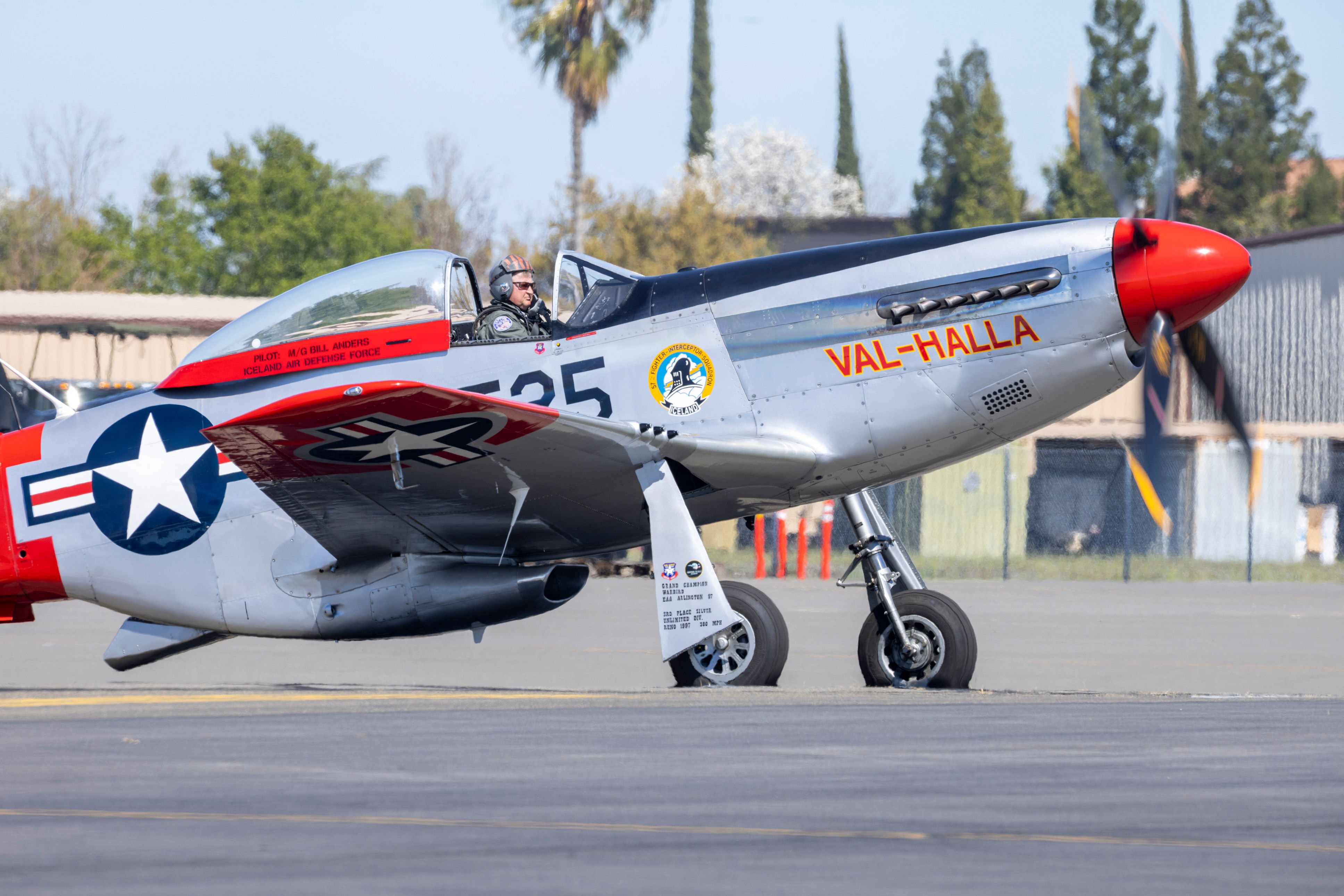 A P-51 Mustang aircraft on the tarmac with a pilot, ready for takeoff.