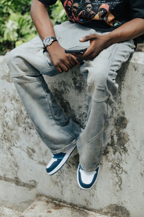 Free Young adult with trendy casual wear, denim pants and sneakers in an urban setting. Stock Photo