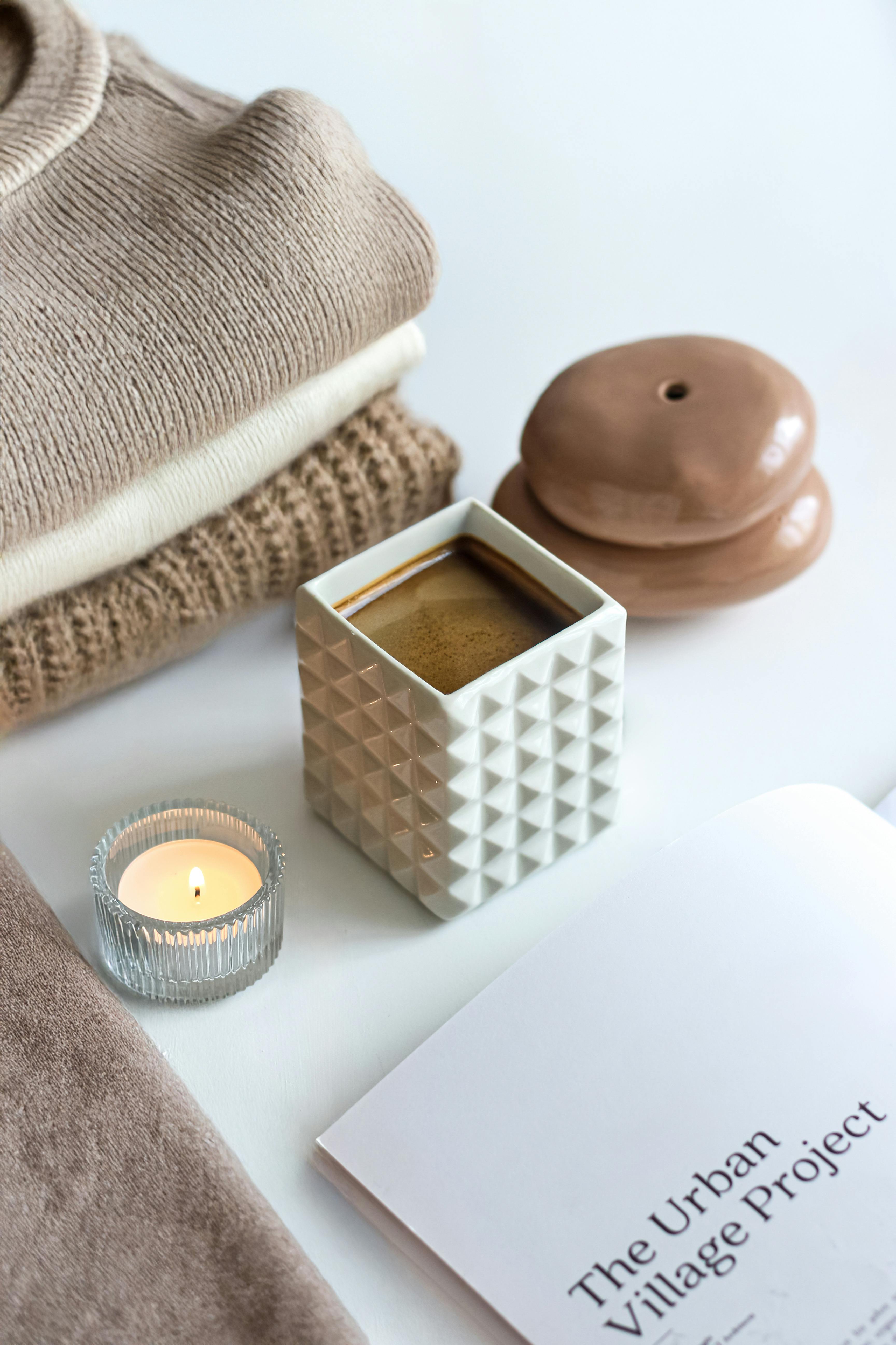 Warm still life setup with coffee, candles, and fashion elements.