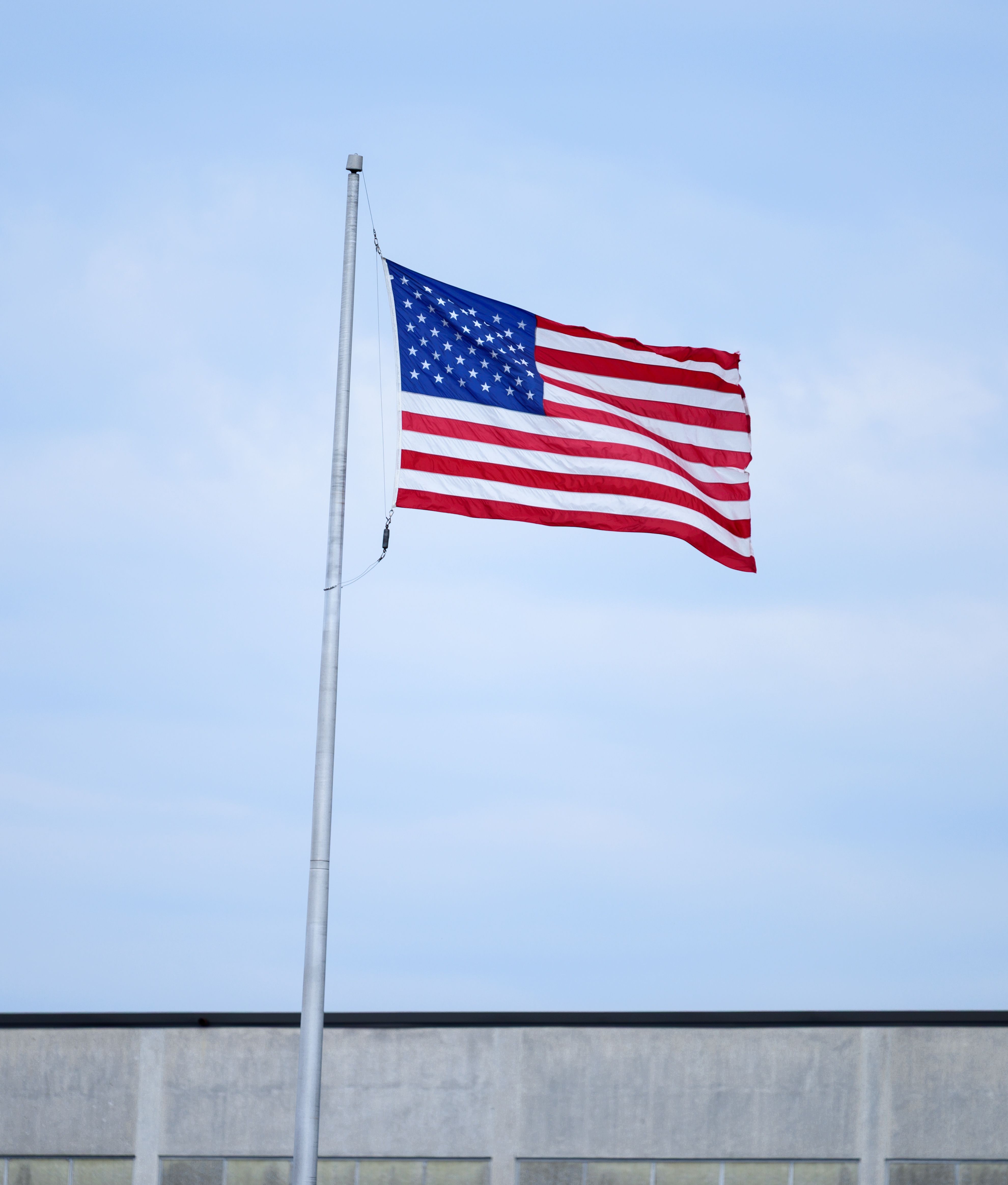 American Flag Waving Under Blue Sky · Free Stock Photo