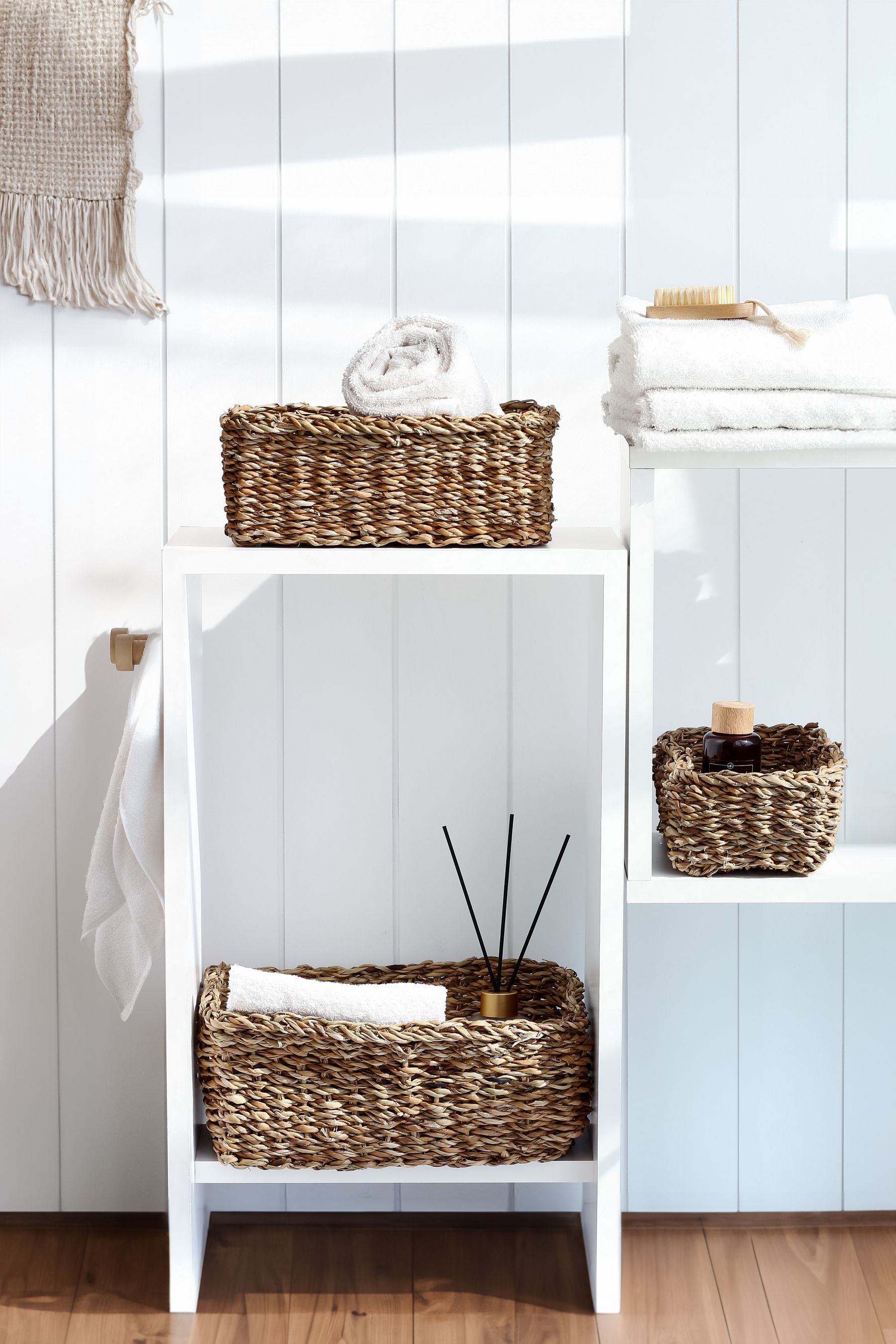 Minimal bathroom shelving organized with woven storage baskets and folded towels