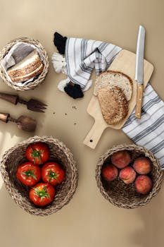 A cozy arrangement of sliced bread, tomatoes, and peaches with rustic wooden utensils on a warm surface.