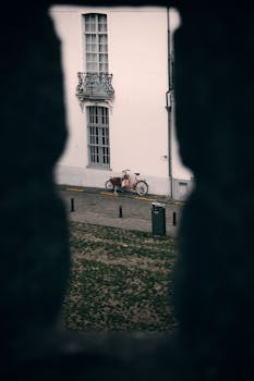 A peaceful scene of a red bicycle next to an elegant white building in Ghent, Belgium.