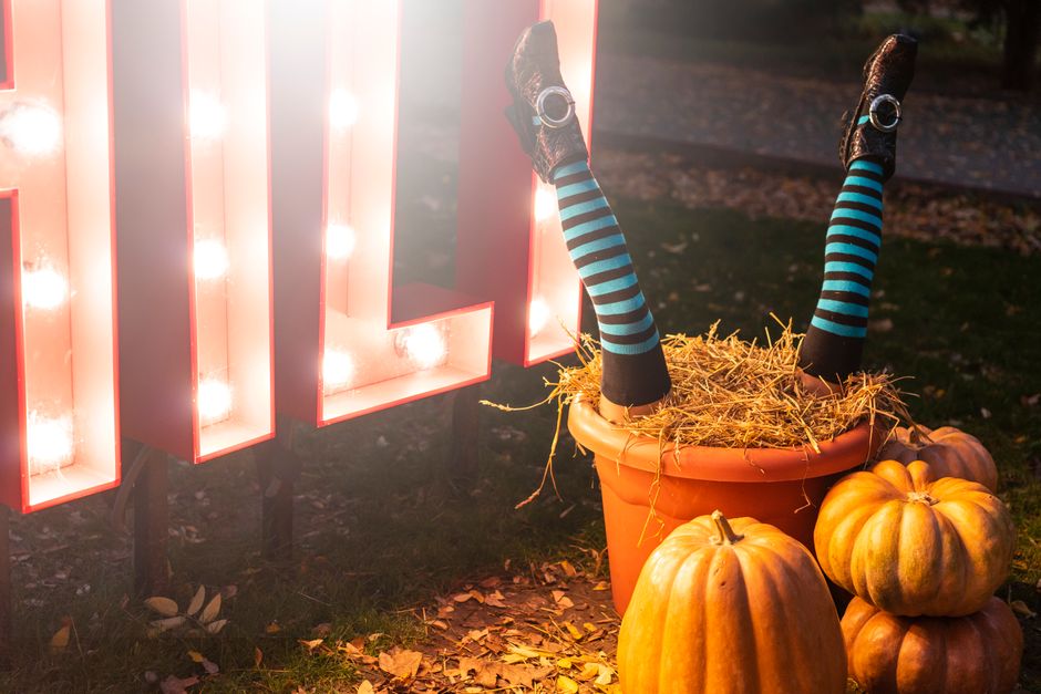 Festive Halloween scene featuring witch's feet, pumpkins, and bright lights creating a spooky atmosphere.