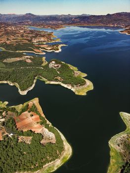 Dramatic aerial photo of a serene lake surrounded by lush landscape and farmland.