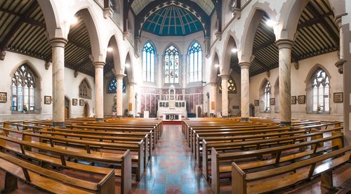 Free Panoramic view of a historic church interior showcasing stained glass windows and wooden pews in Stockport, UK. Stock Photo