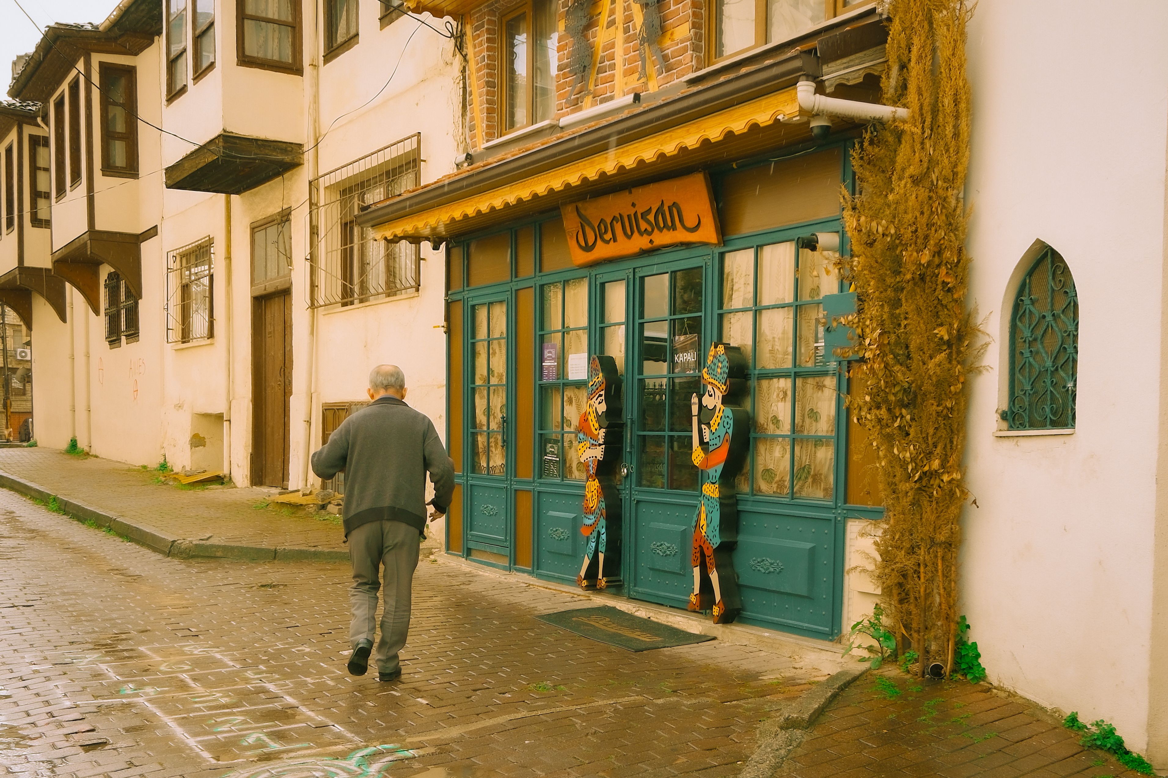 A senior man walks towards a traditional shop in Bursa, Turkey, showcasing Ottoman architecture.