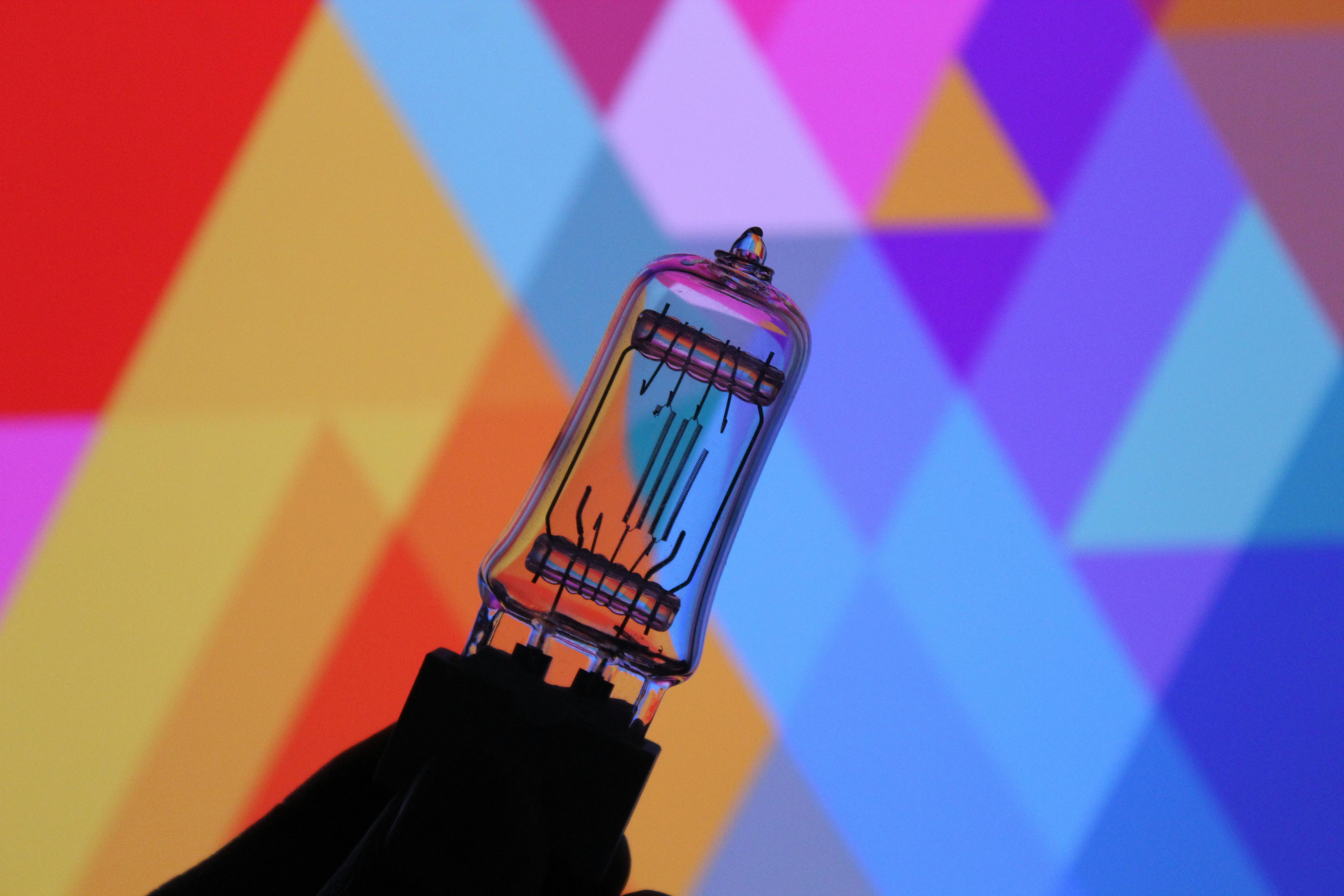 Gratis Tubo di vetro su uno sfondo geometrico astratto colorato, tonalità vivide. Foto a disposizione