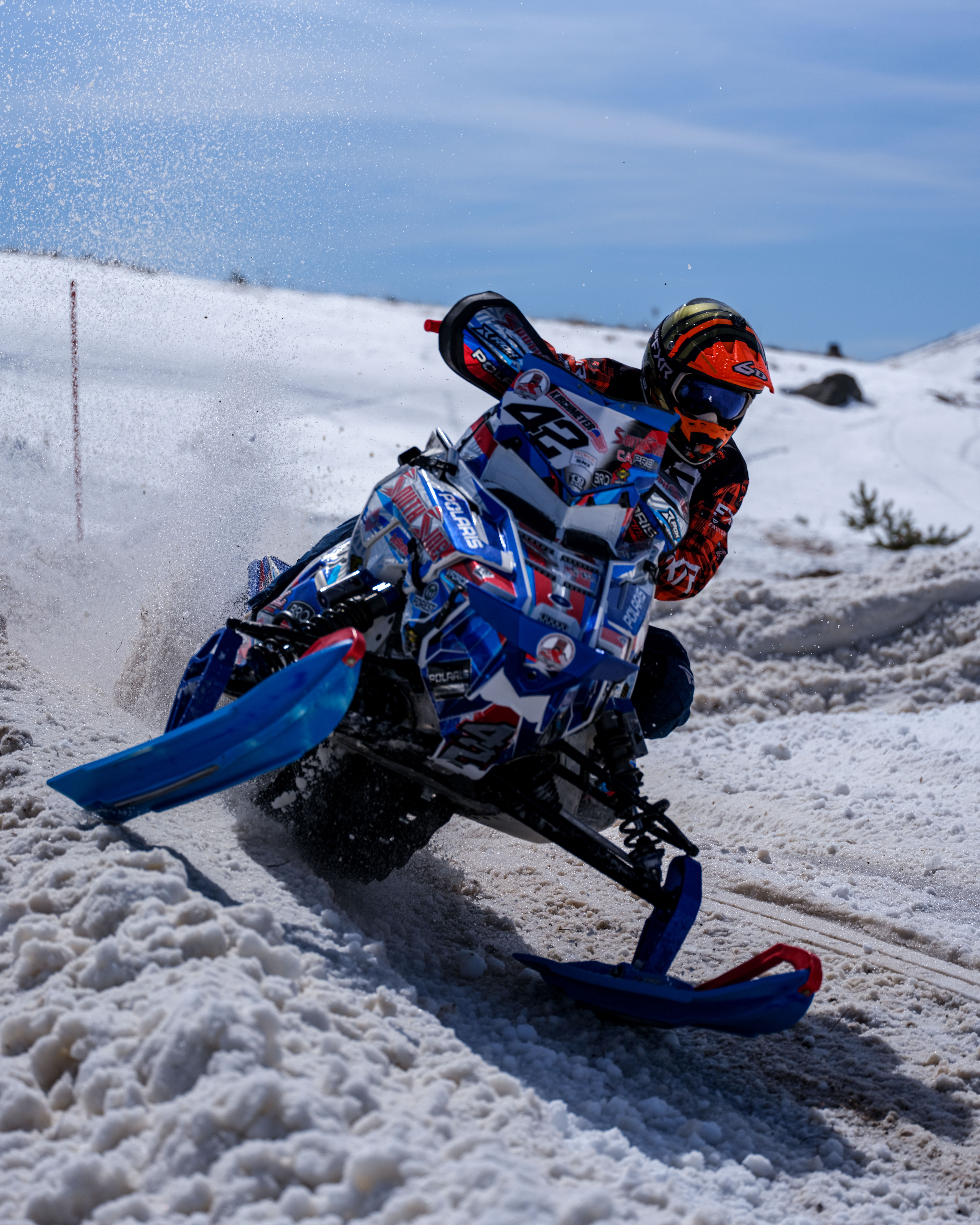 Thrilling snowmobile race with rider navigating snowy terrain, showcasing speed and skill.