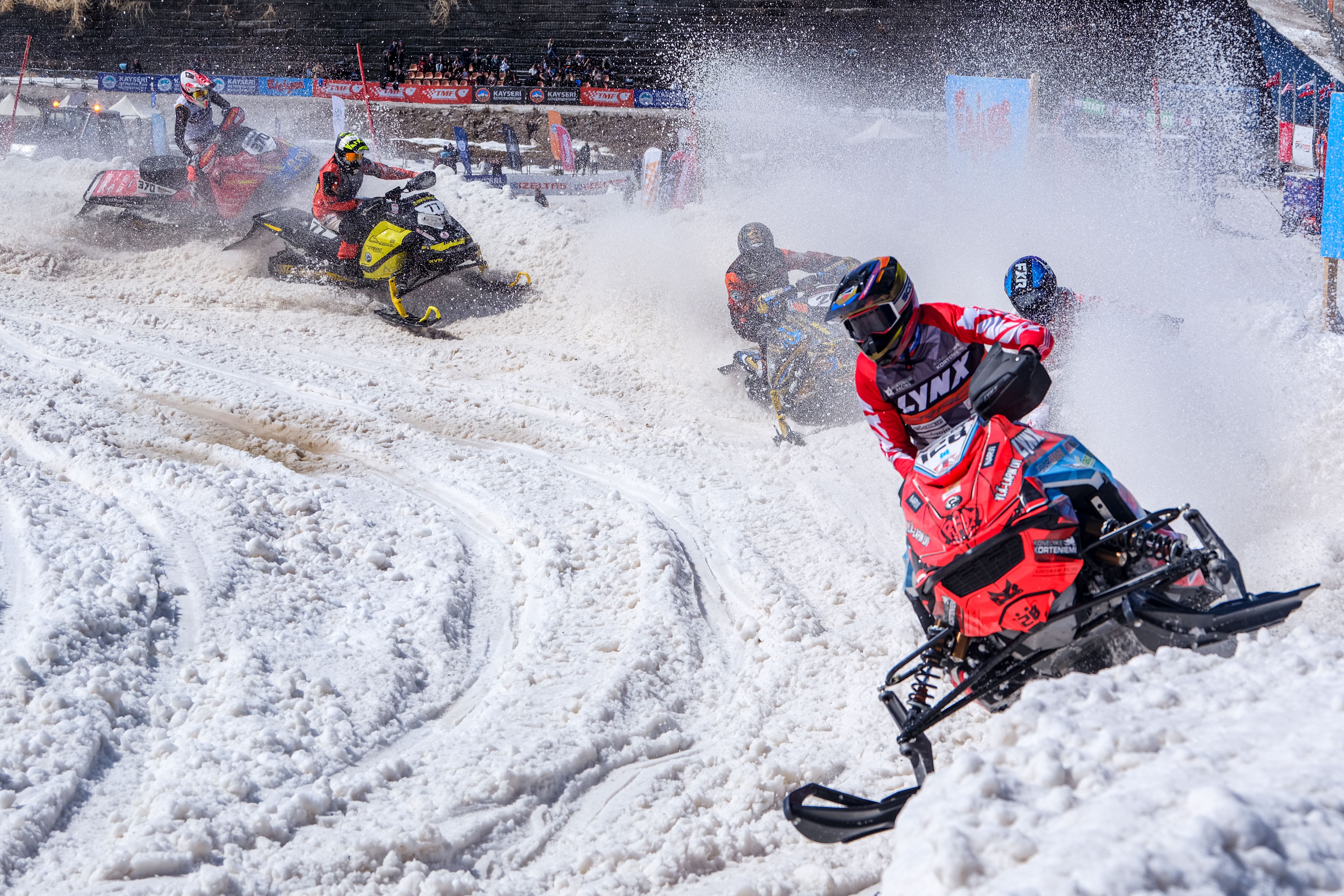 Exciting snowmobile race with riders speeding on a snowy track, capturing dynamic winter sports action.