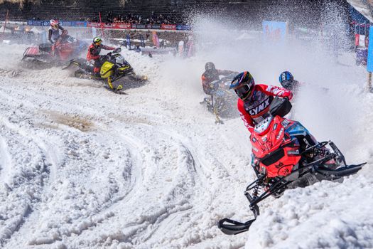 Exciting snowmobile race with riders speeding on a snowy track, capturing dynamic winter sports action.