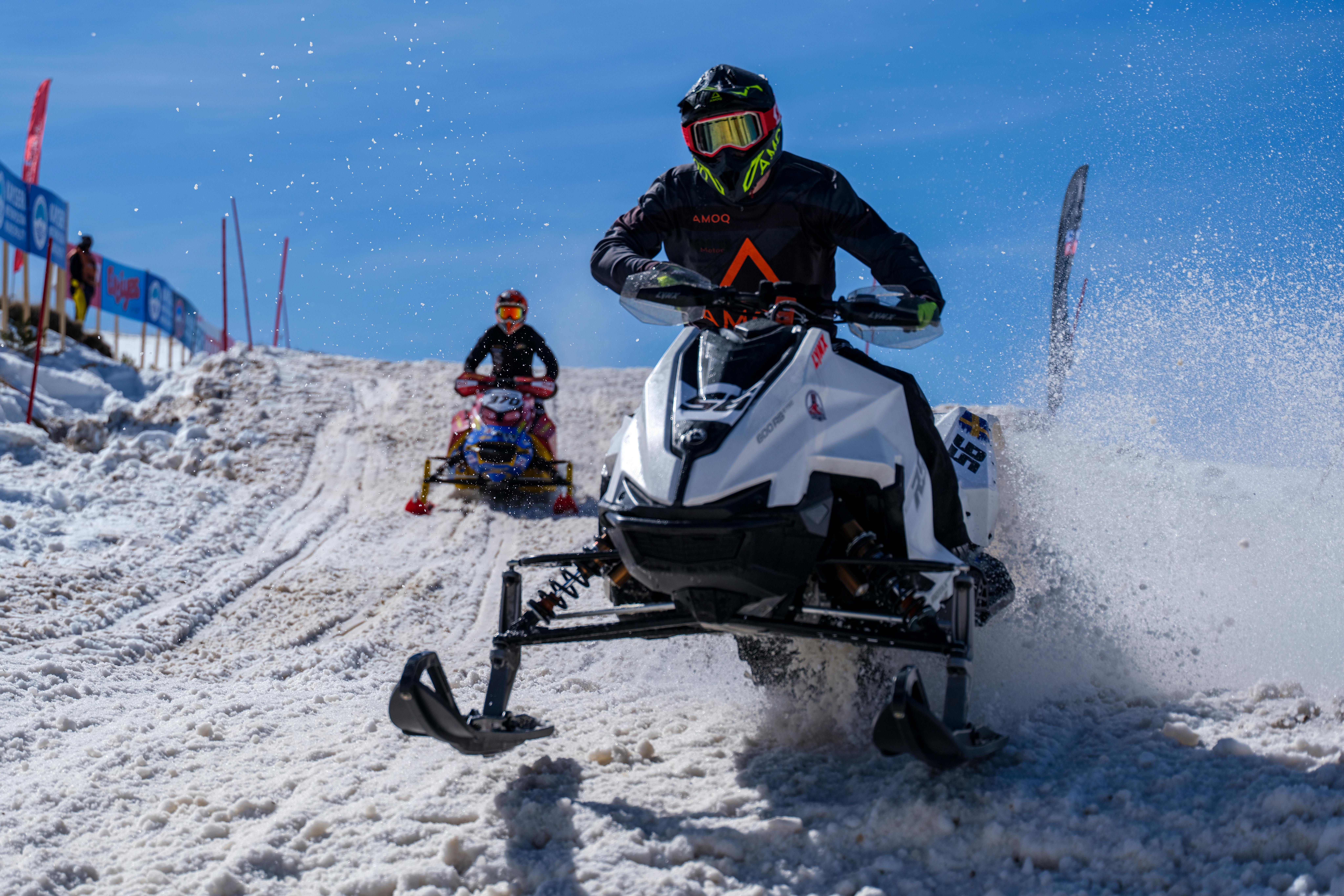 Thrilling snowmobile race on snowy hills with riders in action, capturing the excitement of winter sports.