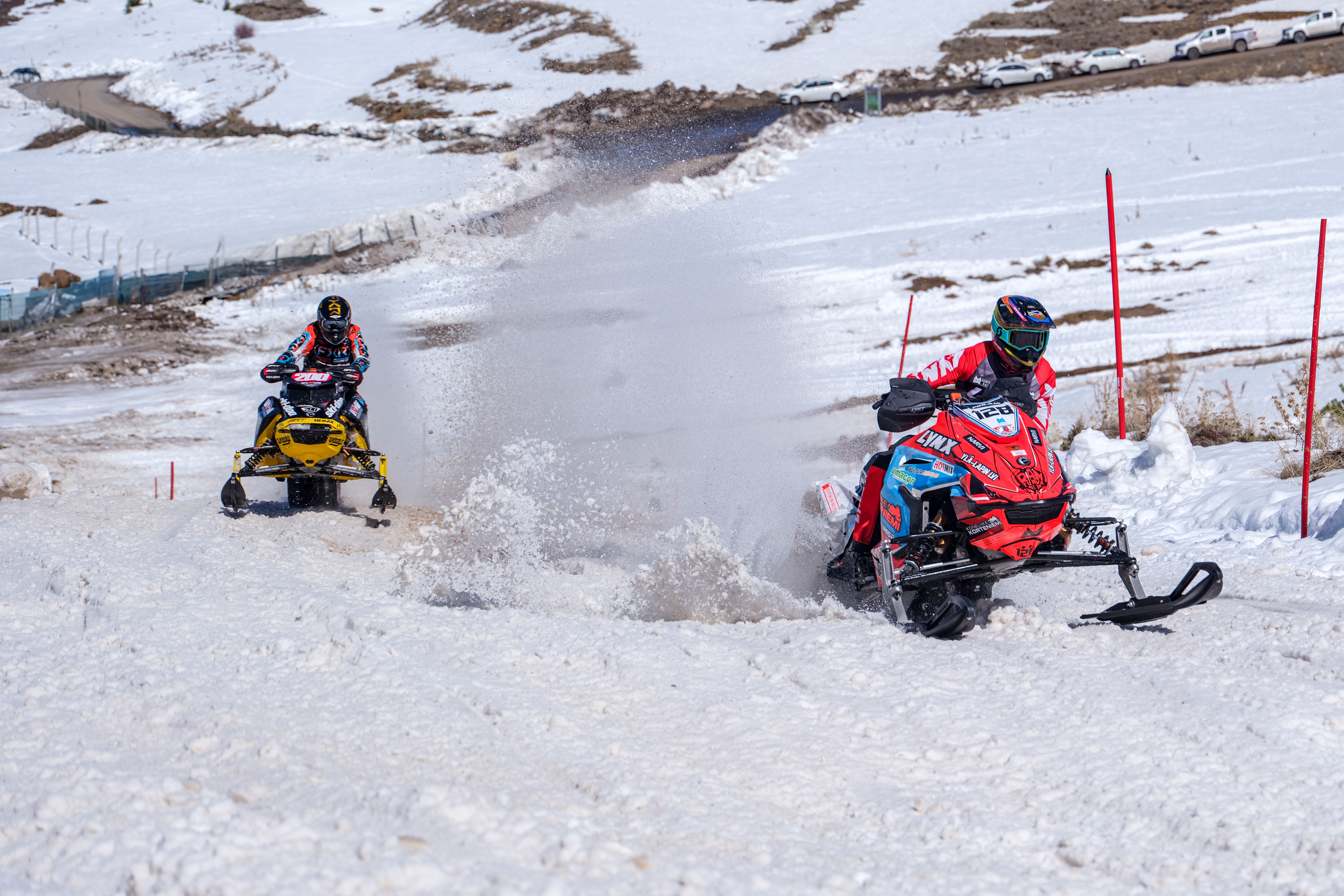 Snowmobiles race through a snowy mountain course in a thrilling winter sports competition.