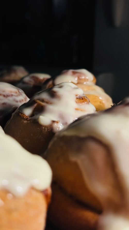 Free Mouth-watering close-up of freshly baked cinnamon rolls topped with creamy icing. Stock Photo