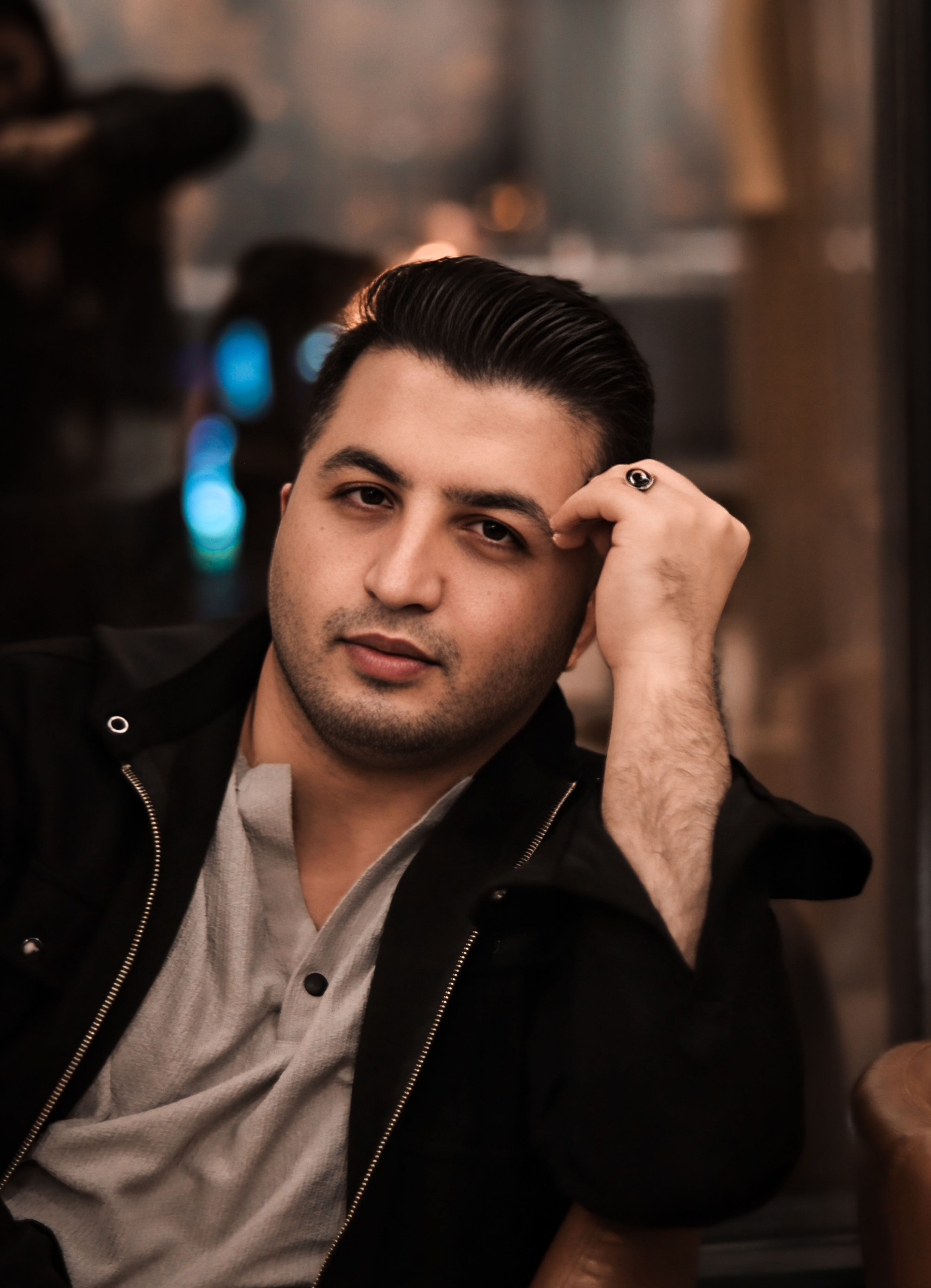 Casual and thoughtful portrait of a man in a dimly lit indoor setting, looking into the camera.