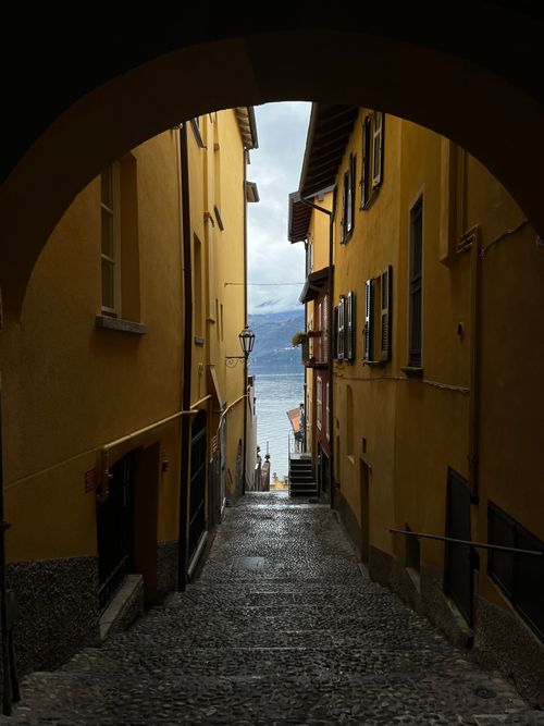 Free Picturesque cobblestone alleyway in Varenna, Italy, leading to Lake Como view. Stock Photo