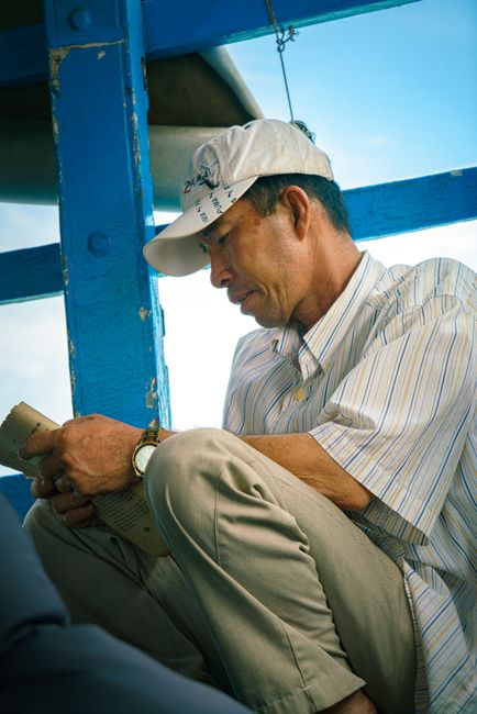 Candid shot of a Vietnamese man reading on a boat in Ho Chi Minh City.