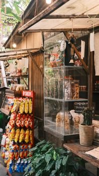 Explore a rustic outdoor market stall with snacks, plants, and hanging lights. - Fotografer Sidoarjo