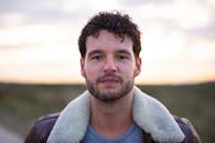 一名男子穿着皮夹克，在模糊的户外背景下拍摄的特写肖像