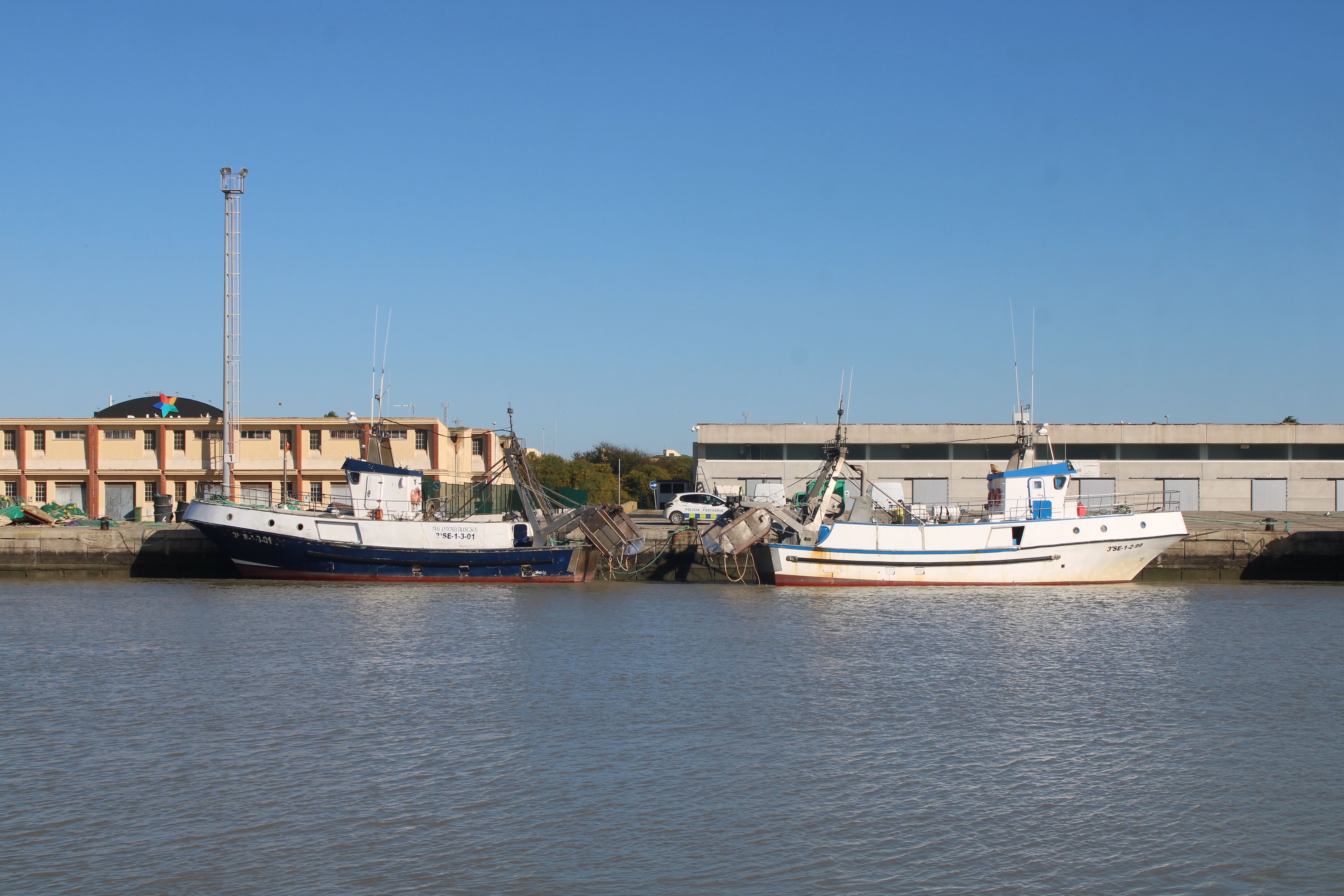 Fishing vessels docked at El Puerto de Santa María with clear blue sky.