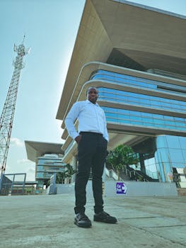 Businessman poses outside a contemporary office building on a sunny day.