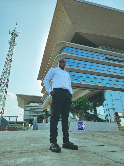 Free Businessman poses outside a contemporary office building on a sunny day. Stock Photo