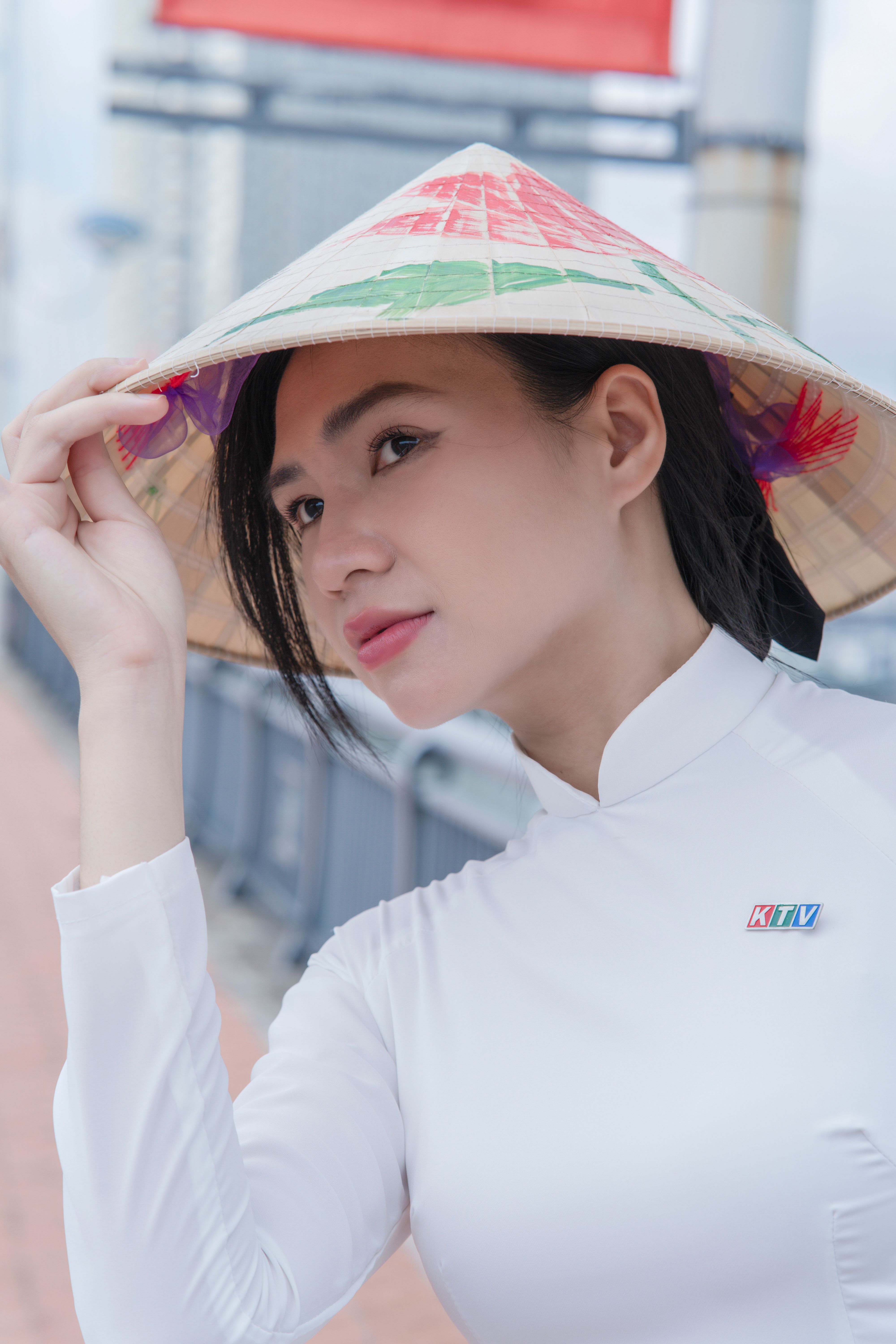 Portrait of a woman in a traditional Vietnamese conical hat outdoors.