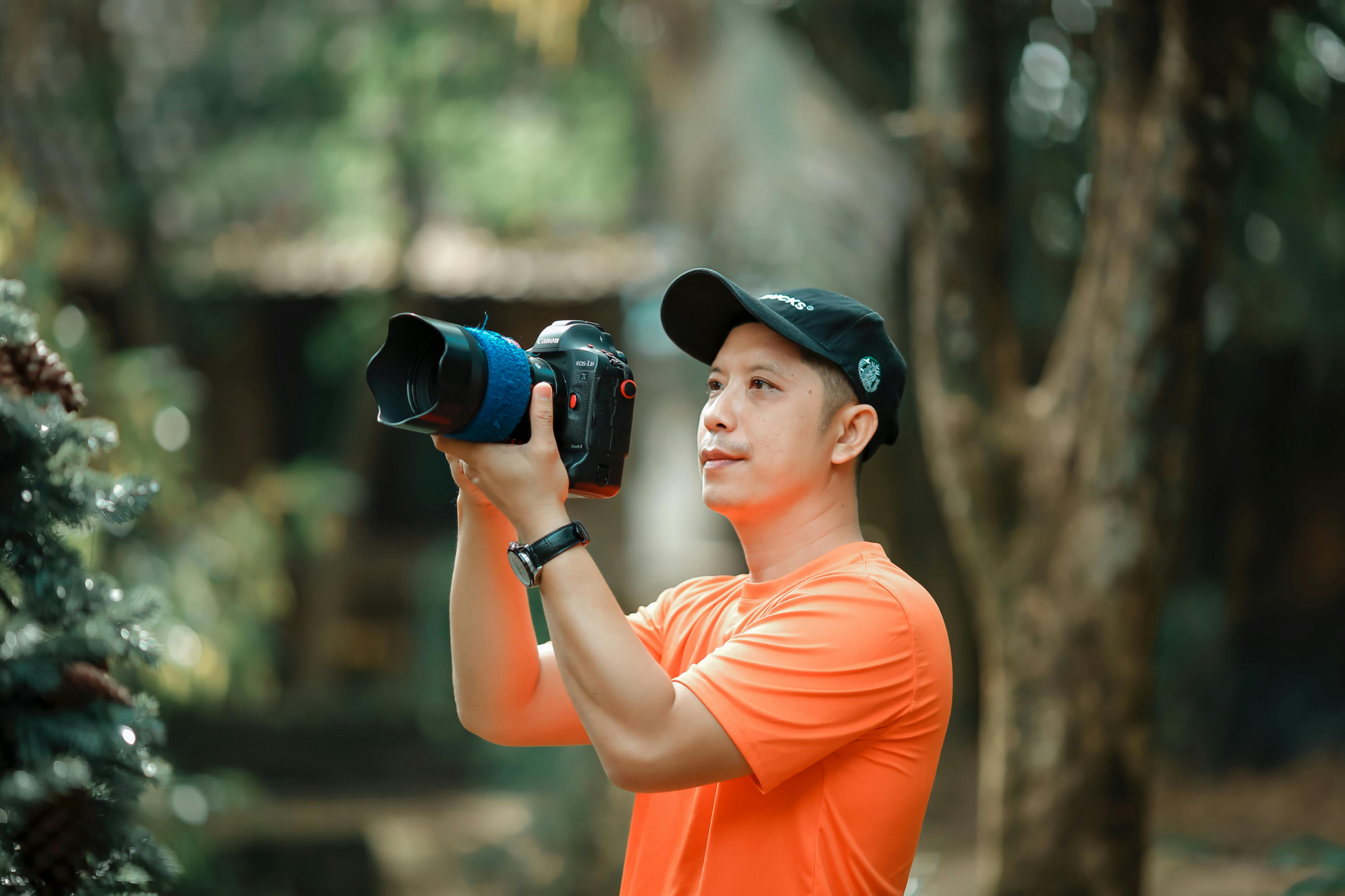 A professional photographer taking outdoor pictures in a lush, green setting.