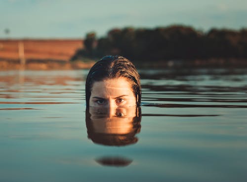 Woman Sticking Half of Her Face Out of Body of Water