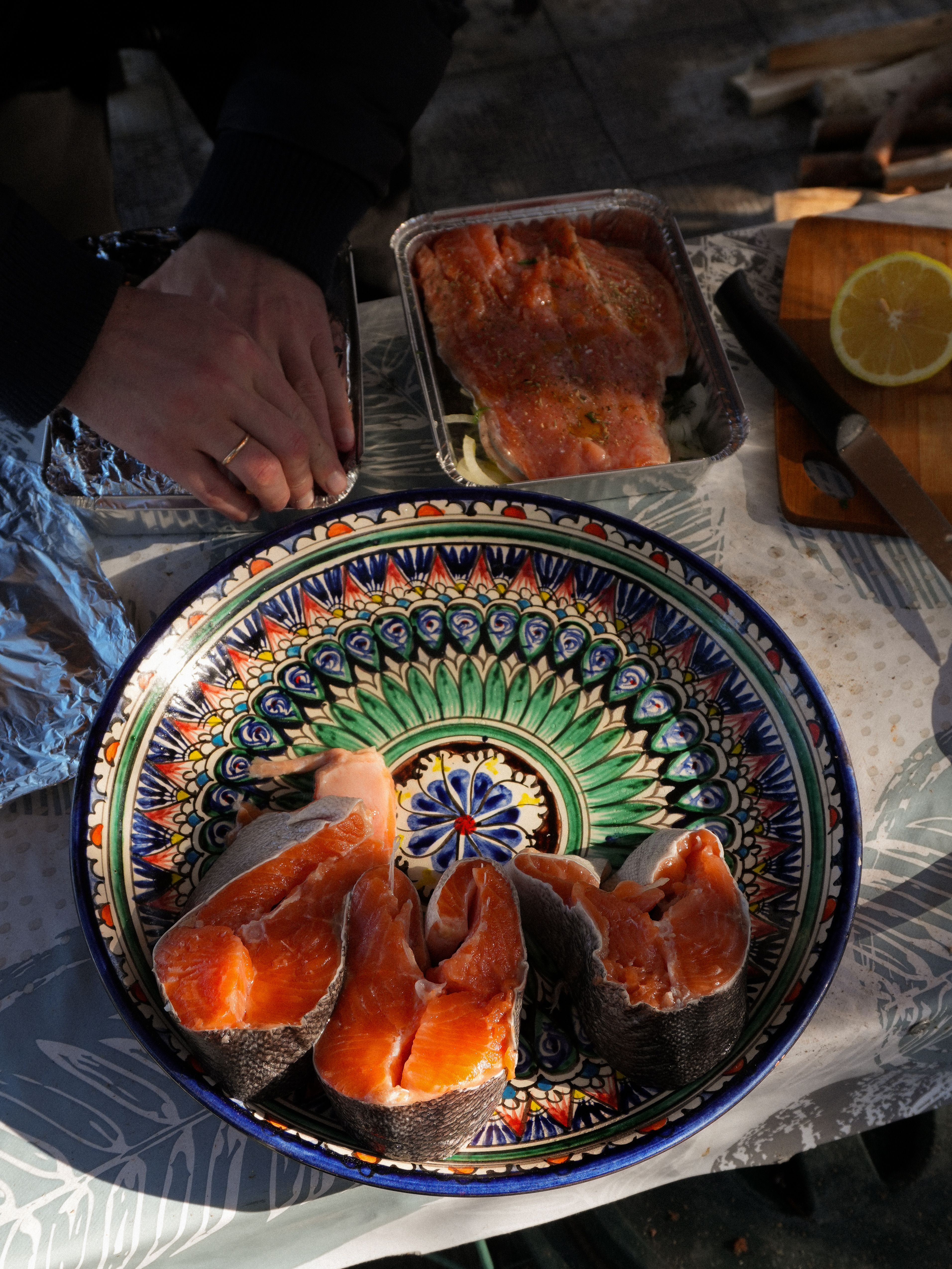 Colorful plate with fresh salmon fillets outdoors, ready for cooking.