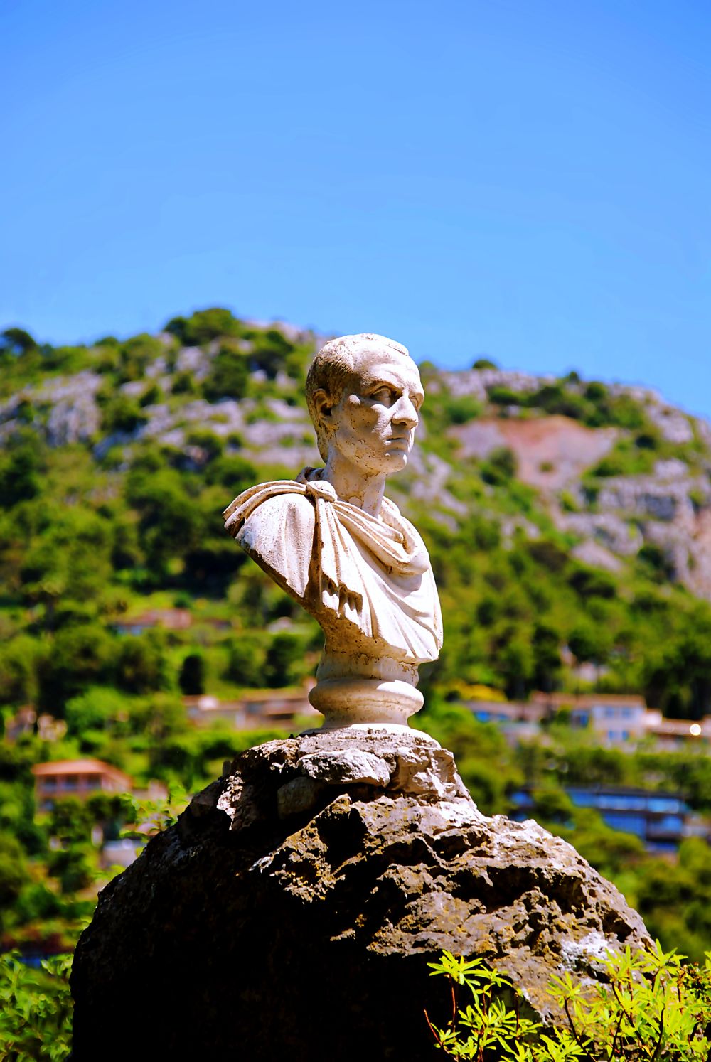 Statuie de piatră între plante, în grădina exotică din Èze