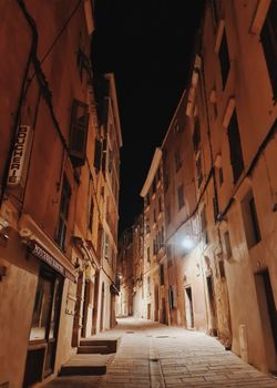 A serene nighttime view of a narrow alley in a historic European town, warmly lit street.