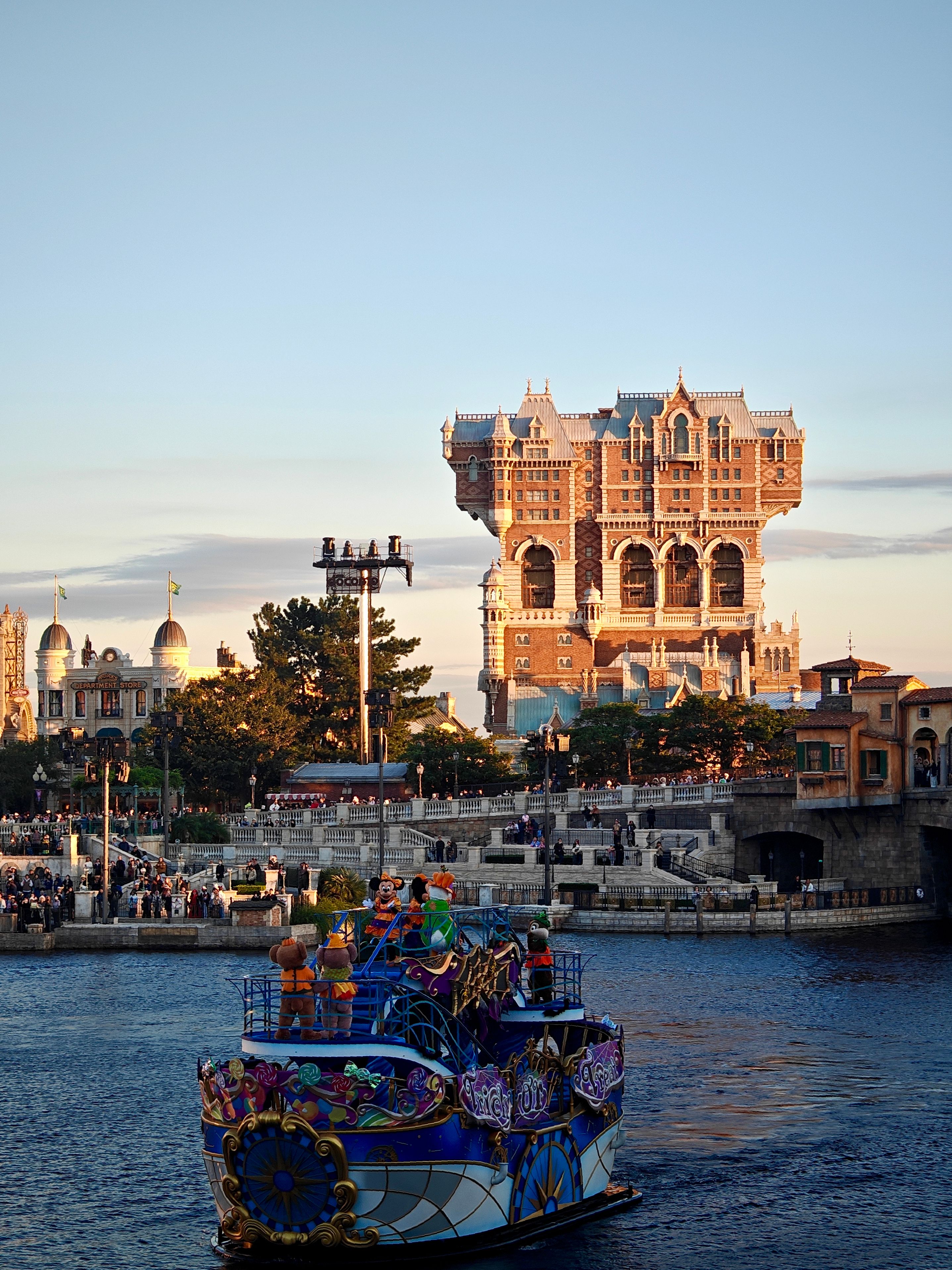 A vibrant boat sails near the iconic Tower of Terror at DisneySea during daytime.