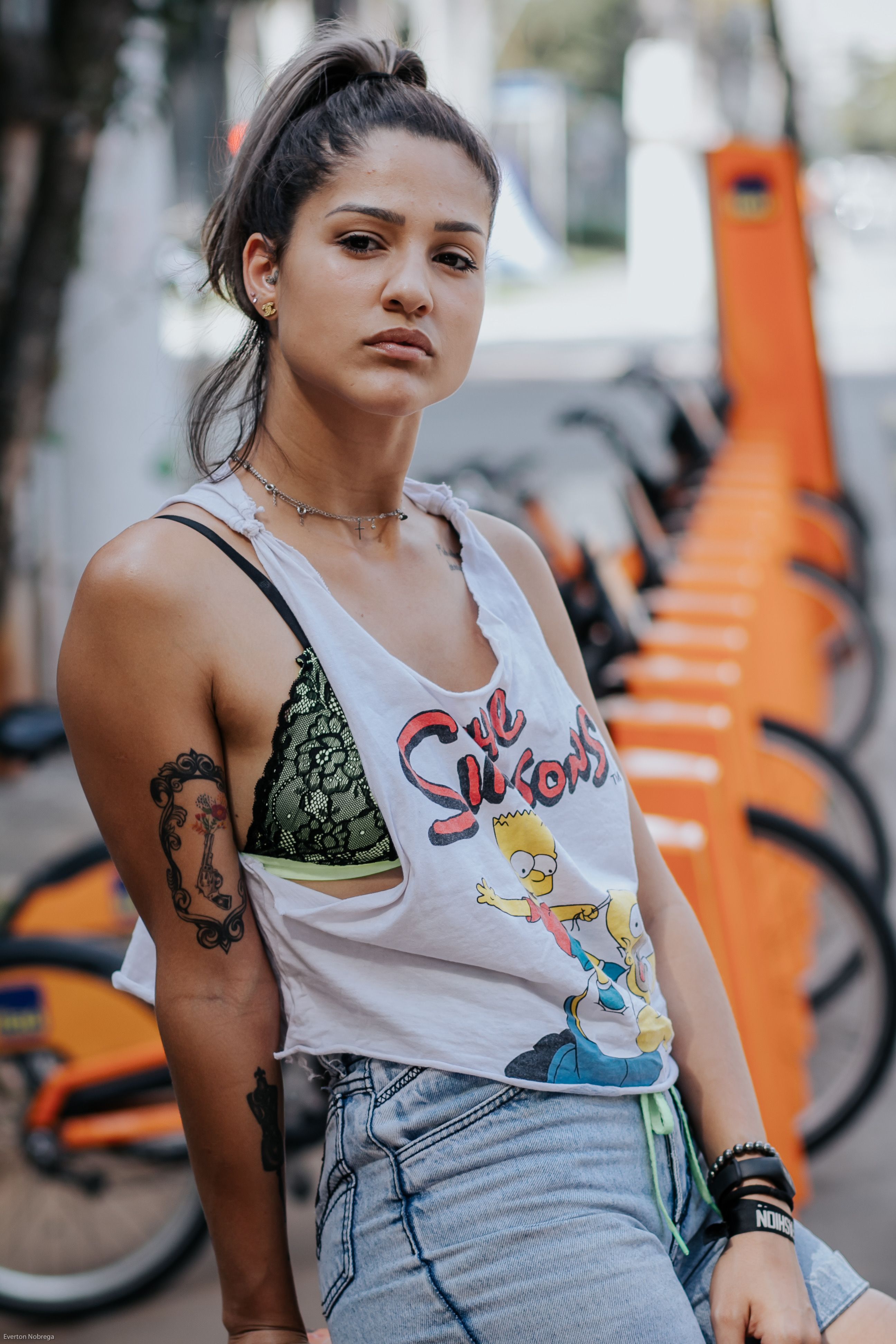 一位自信的年轻女性身着休闲装，纹身外露，在户外摆出姿势，散发着现代时尚气息