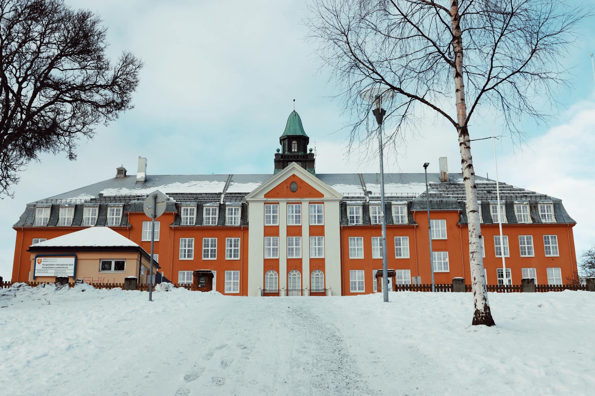 Beautiful winter view of historic building in Tromsø, Norway covered in snow and blue sky.