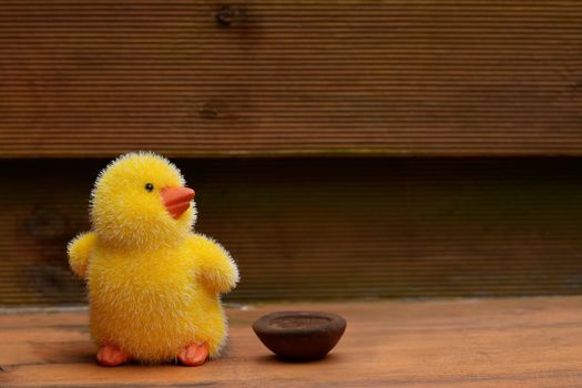 Adorable fluffy yellow chick toy on a wooden surface, perfect for Easter decor.