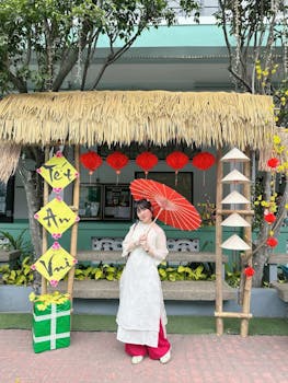 Woman in white ao dai holding red umbrella in Tet festival decoration outdoors.