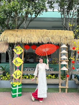 Woman holding a red umbrella, celebrating Tet festival in traditional Vietnamese dress, under a straw canopy.