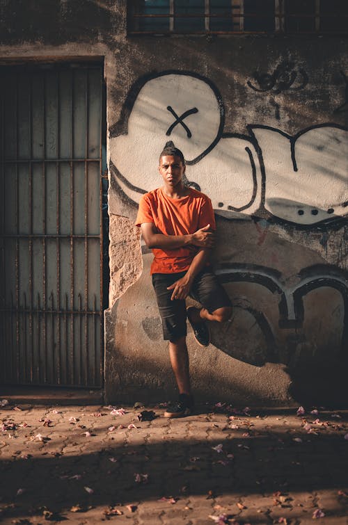 Man Leans on Graffiti Wall